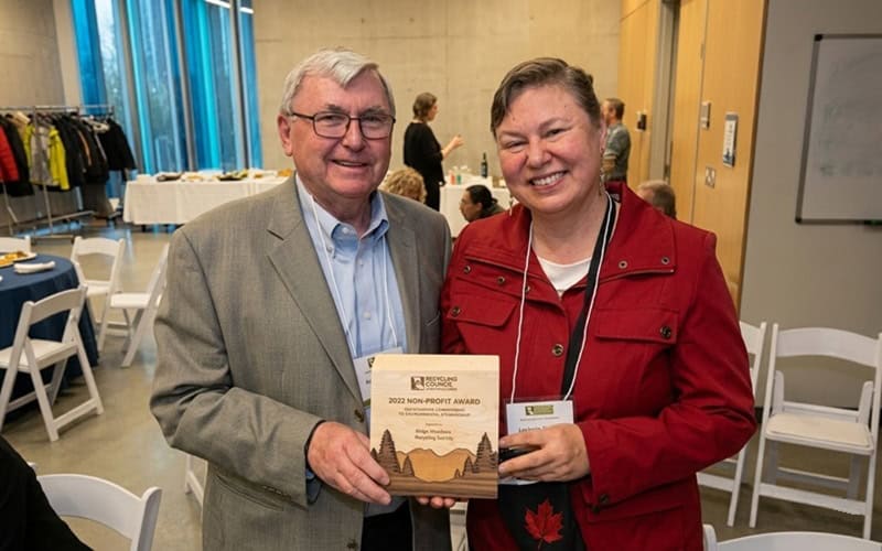 Two smiling individuals holding an award at Ridge Meadows Recycling Society event.