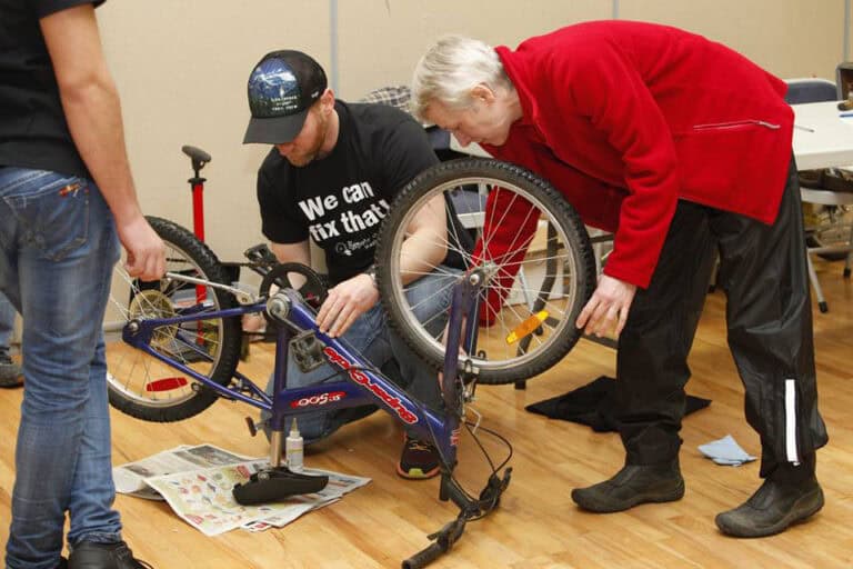Volunteer helping fix a bicycle at the Repair Cafe event.