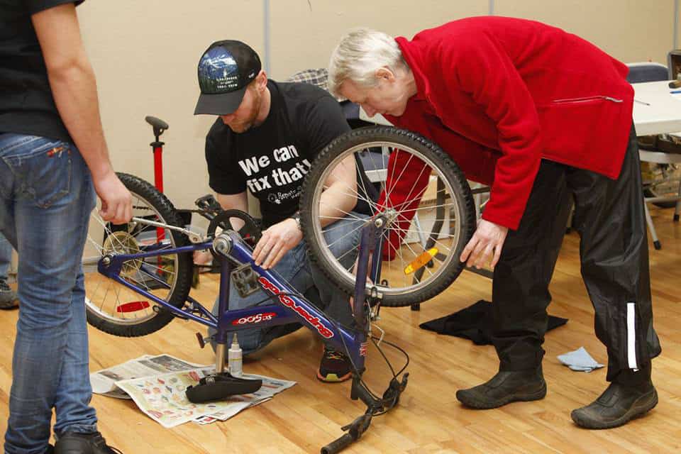 Volunteer helping fix a bicycle at the Repair Cafe event.