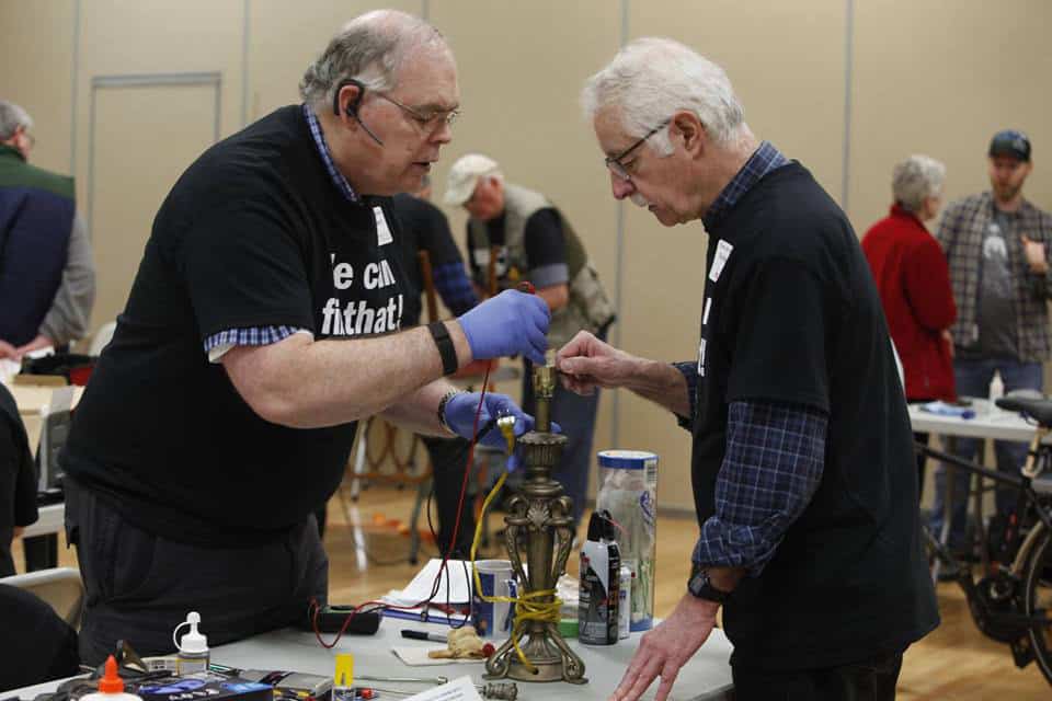 Volunteers repairing an antique lamp at the Repair Cafe event.